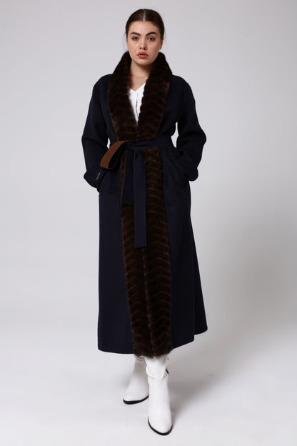 Woman wearing a long alpaca overcoat with mink fur on a white background