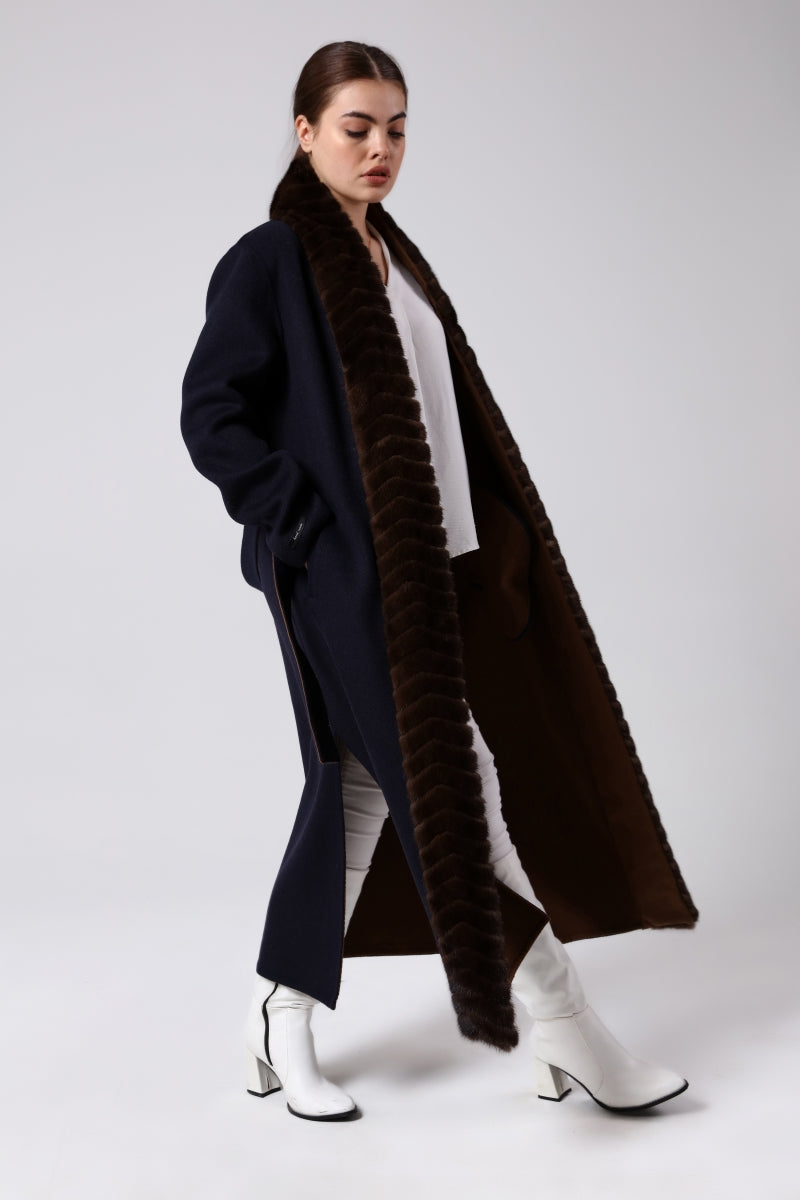 Woman wearing a long alpaca coat with mink fur on a white background