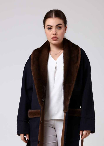 Woman wearing a alpaca overcoat with a mink fur, white pants, and white boots on a white background