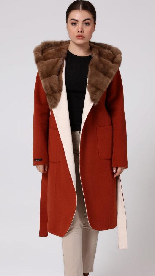 Woman wearing a long red coat with fur hood on a white background