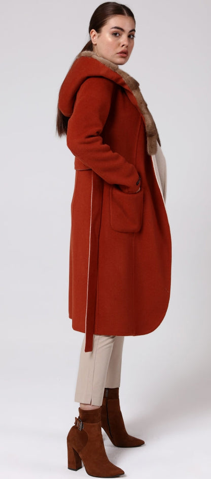Woman wearing a long red coat with a hood on a white background