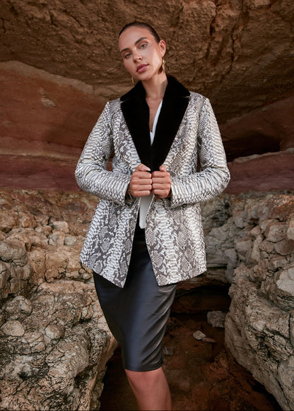 Woman wearing a patterned jacket and black top in a rocky cave setting