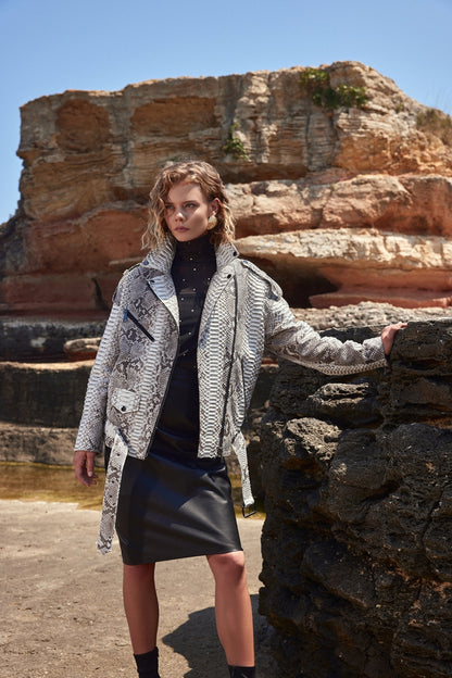 Woman standing in front of a rocky landscape wearing a patterned coat.