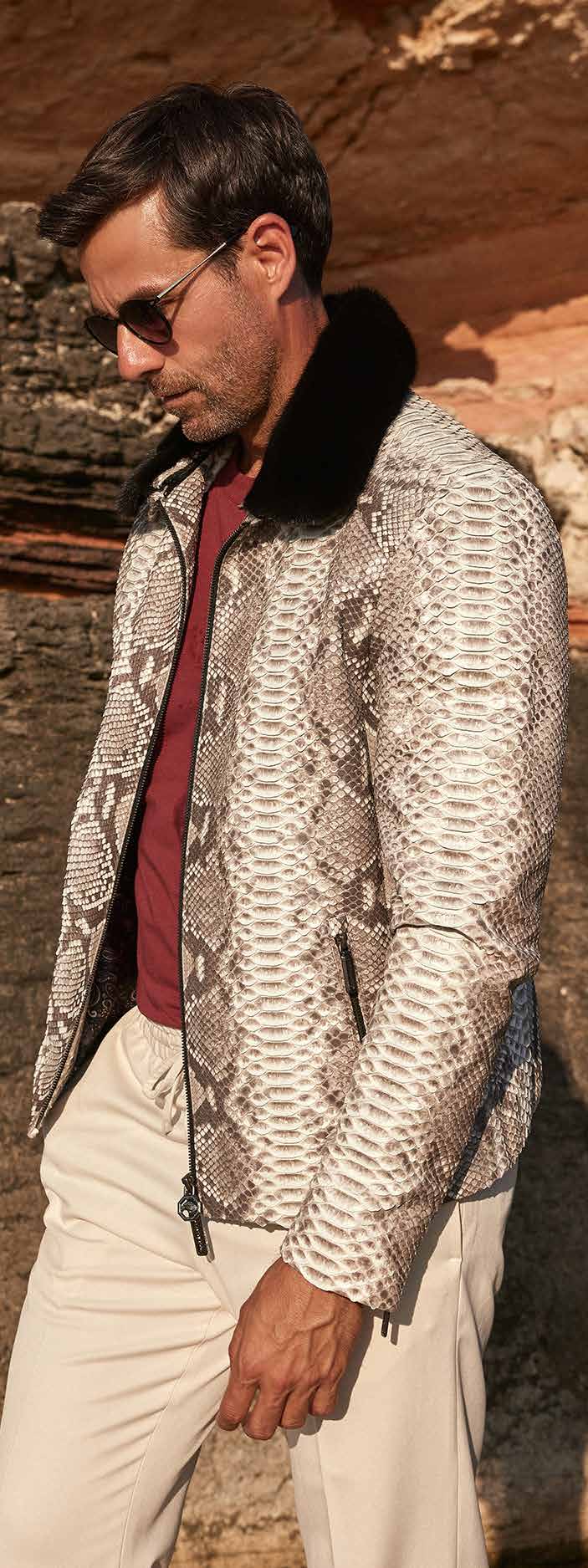 Man wearing a patterned jacket and sunglasses in front of a rocky background