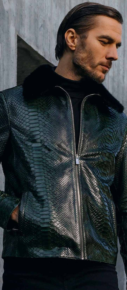 Man wearing a dark green leather jacket with fur collar against a gray wall.