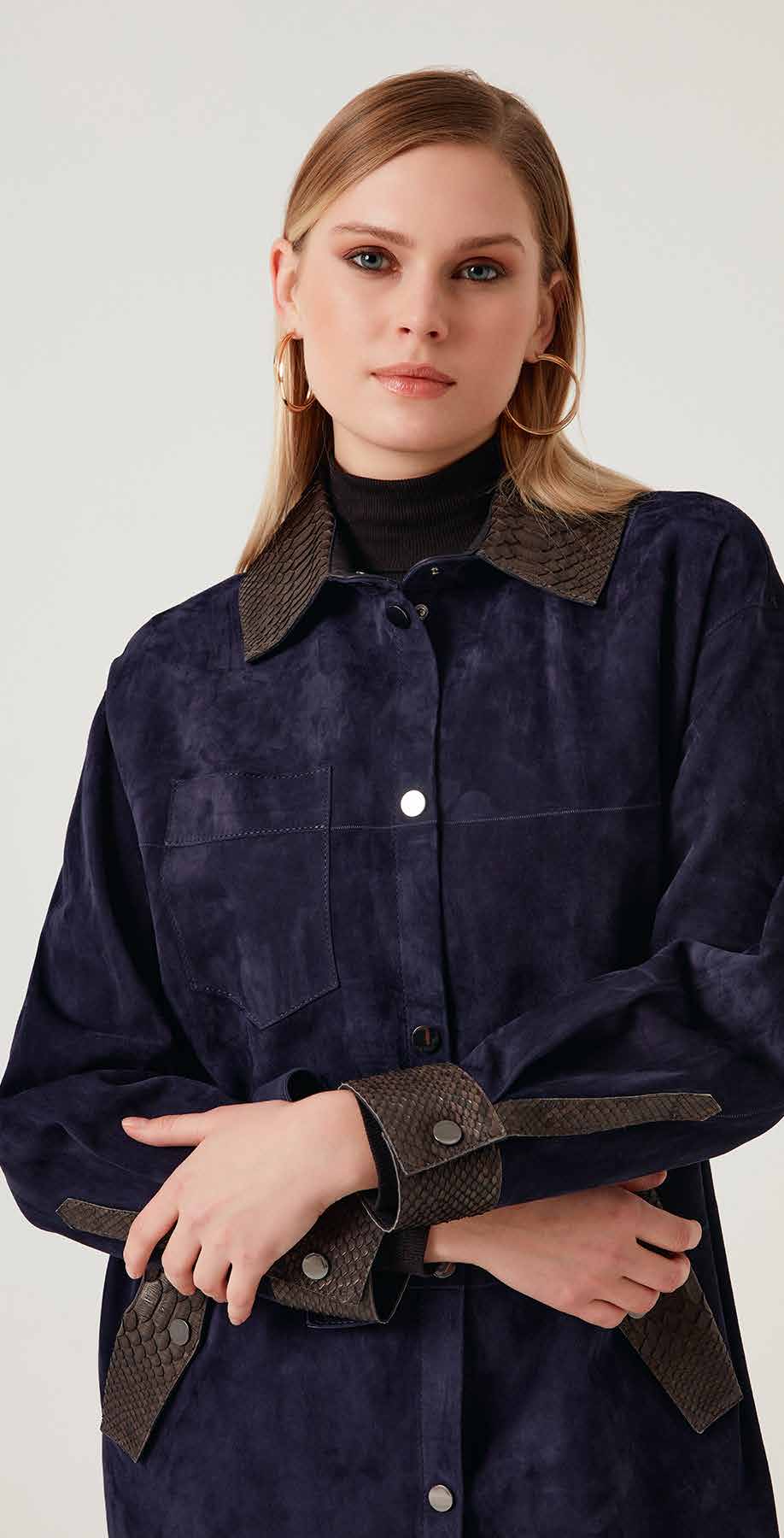 Woman wearing a dark blue jacket with brown accents on a white background