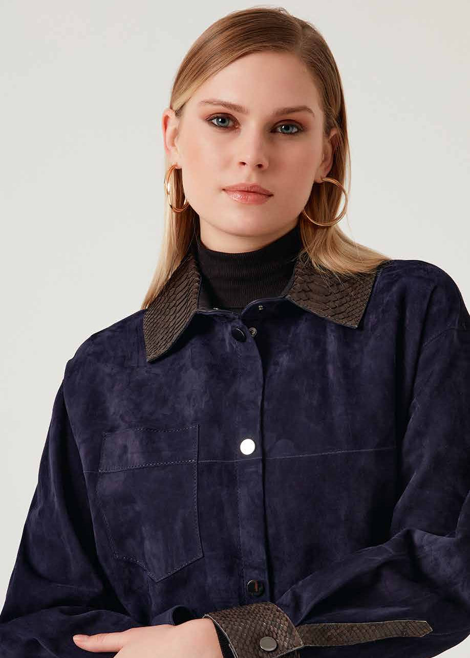 Woman wearing a dark blue jacket with brown accents on a white background