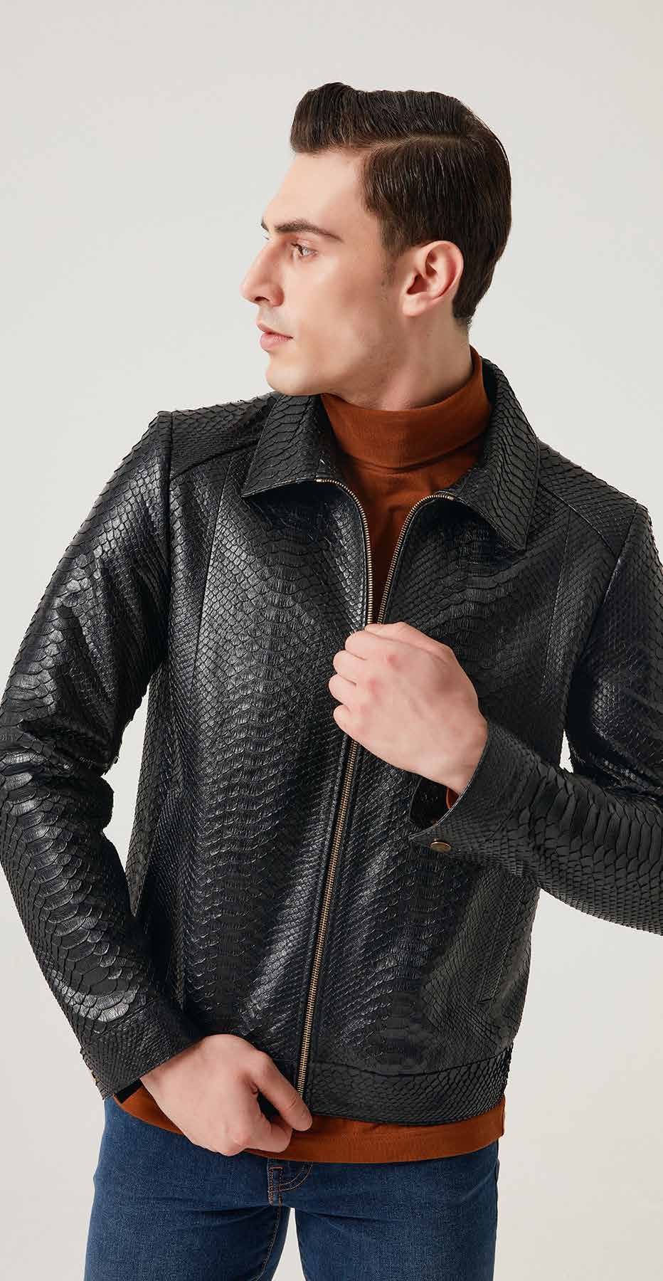 Man wearing a black textured leather jacket over a brown sweater on a light gray background