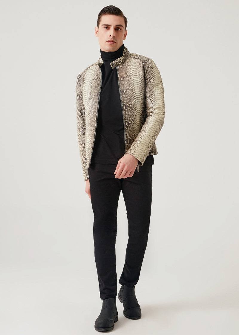 Man wearing a patterned jacket over a black turtleneck and pants on a white background