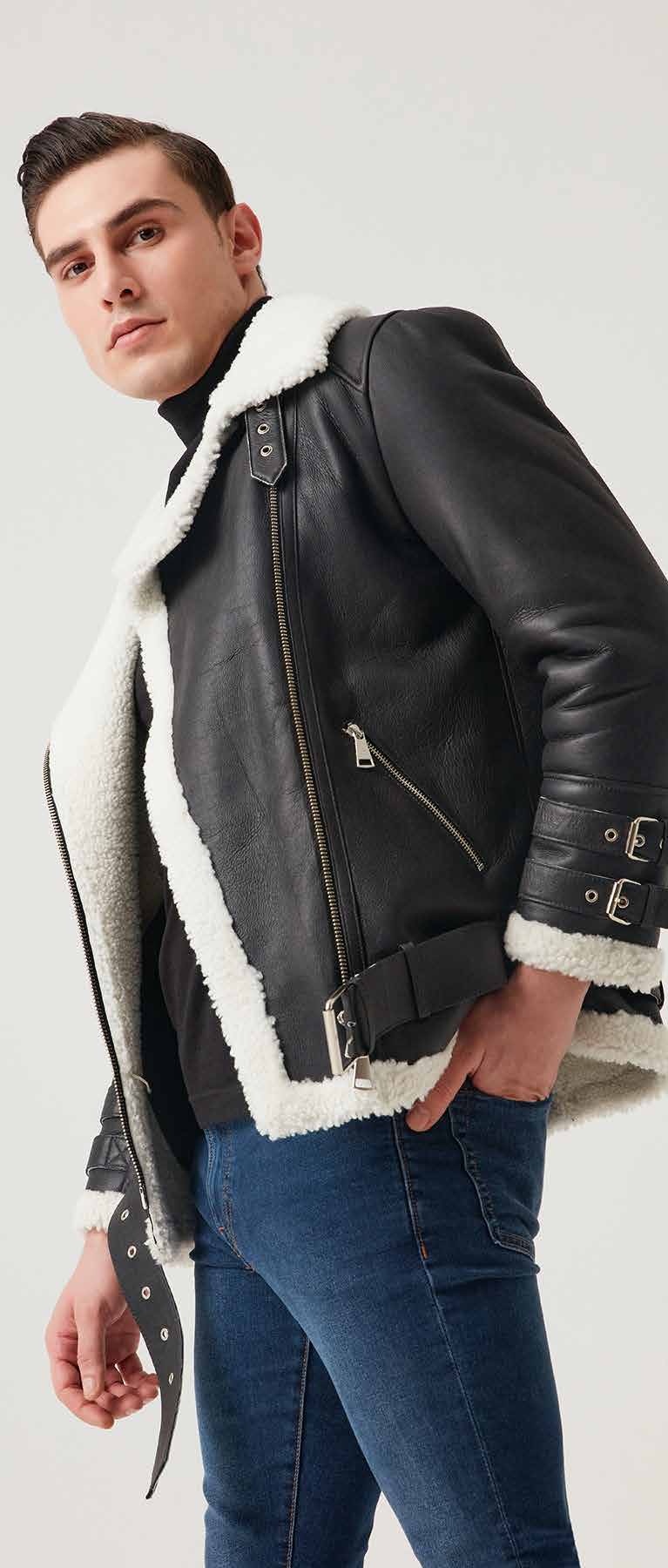 Man wearing a black leather jacket with white fur lining on a plain background