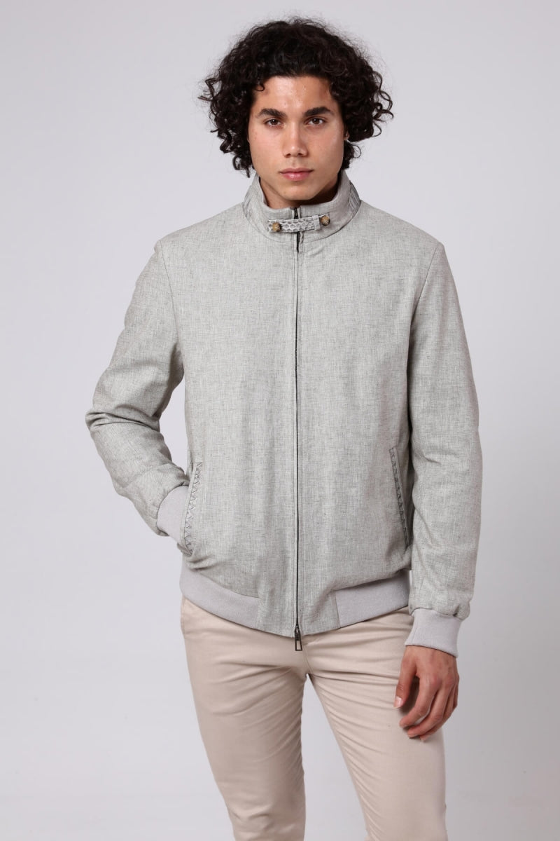 Man wearing a light gray jacket and beige pants on a white background