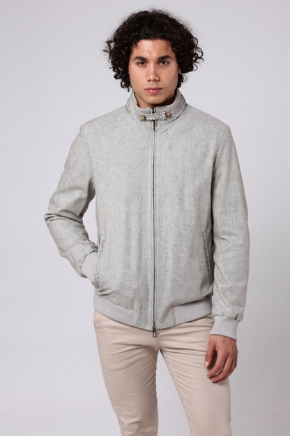 Man wearing a light gray jacket and beige pants on a white background