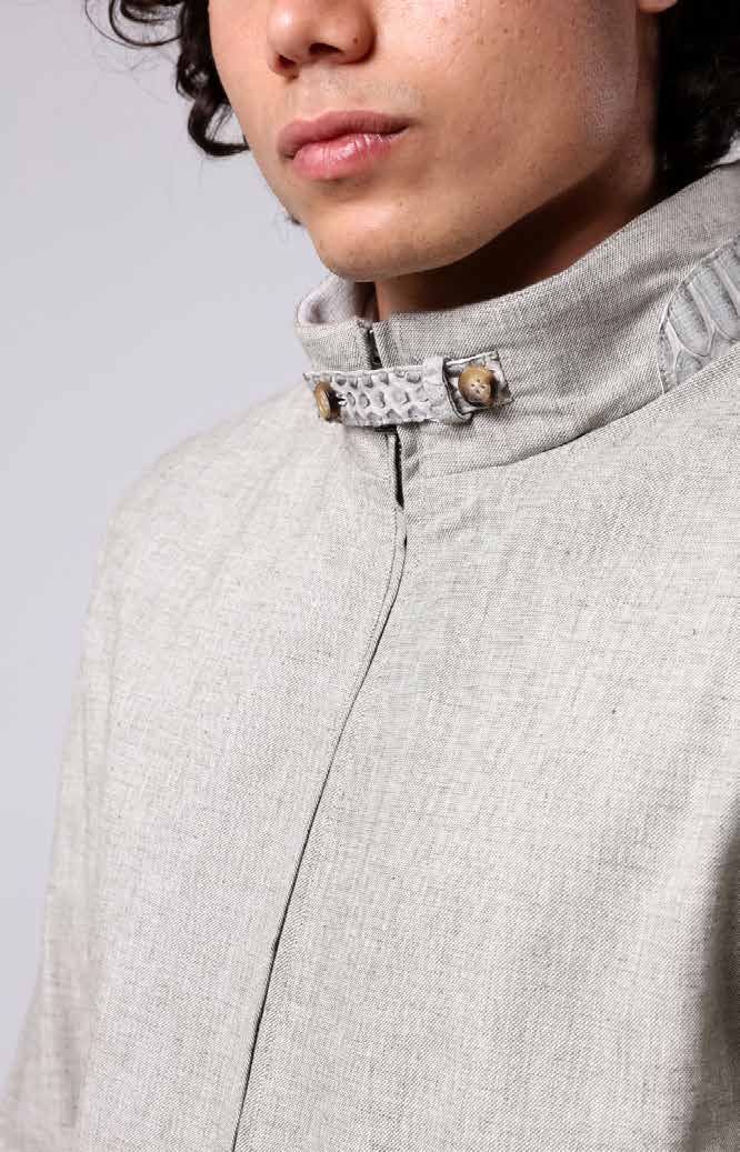 Close-up of a man wearing a light gray jacket with a textured collar against a plain background