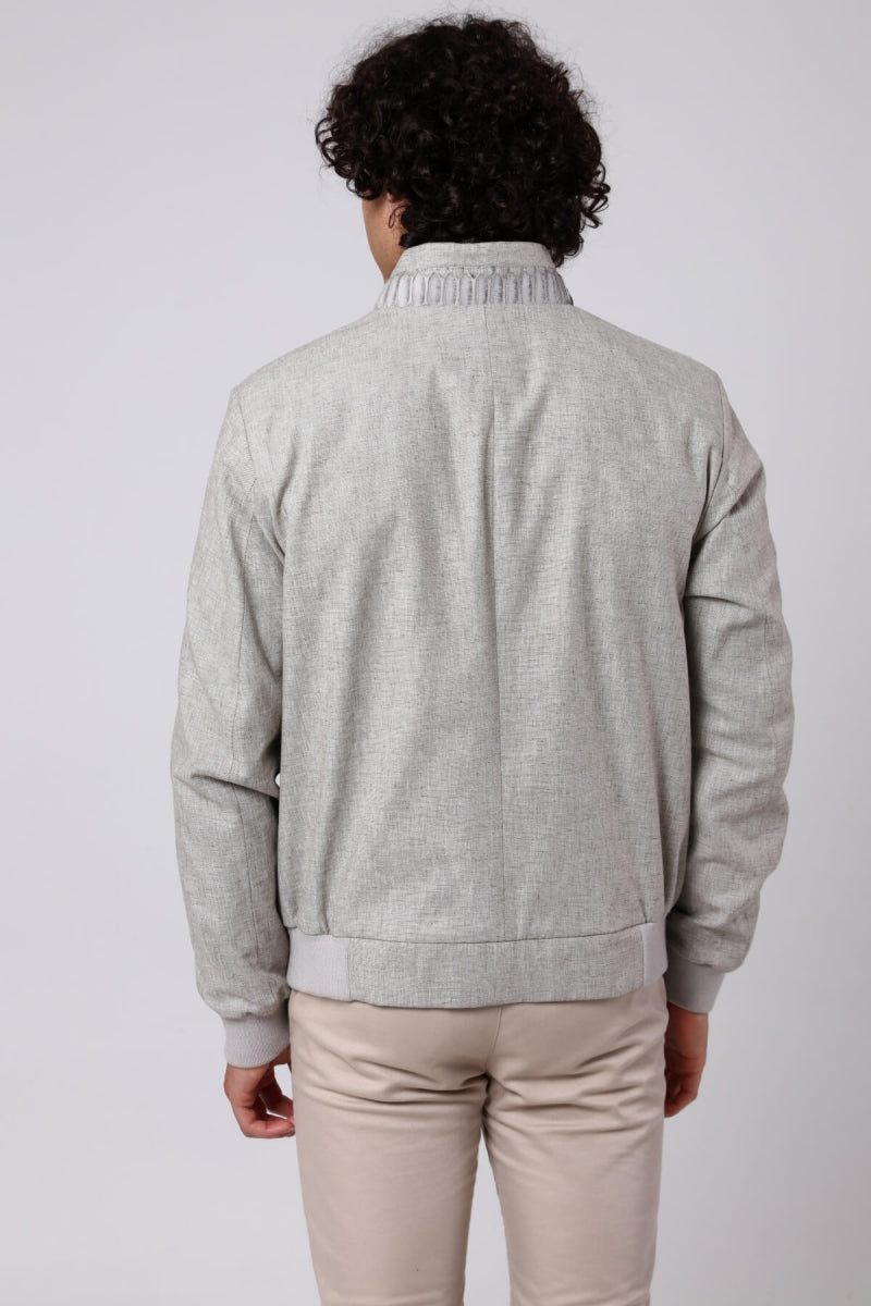 Man wearing a gray sweater and beige pants against a white background