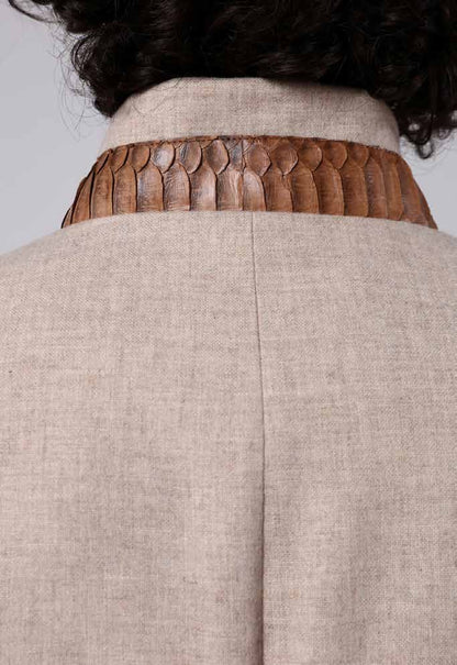 Close-up of a beige garment with a textured brown collar against a gray background
