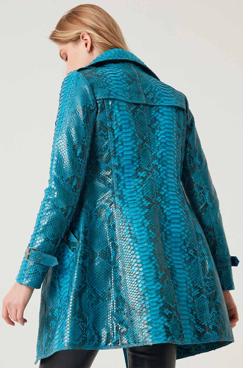 Person wearing a blue phyton leather coat on a plain background