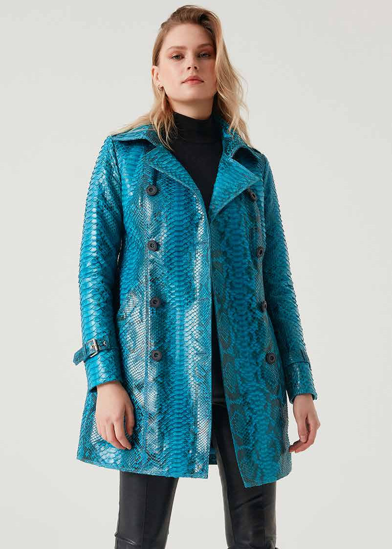 Woman wearing a blue phyton coat and black leather pants on a white background