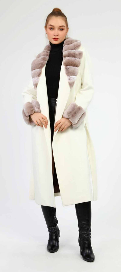 Woman wearing a long cream coat with fur trim on a white background