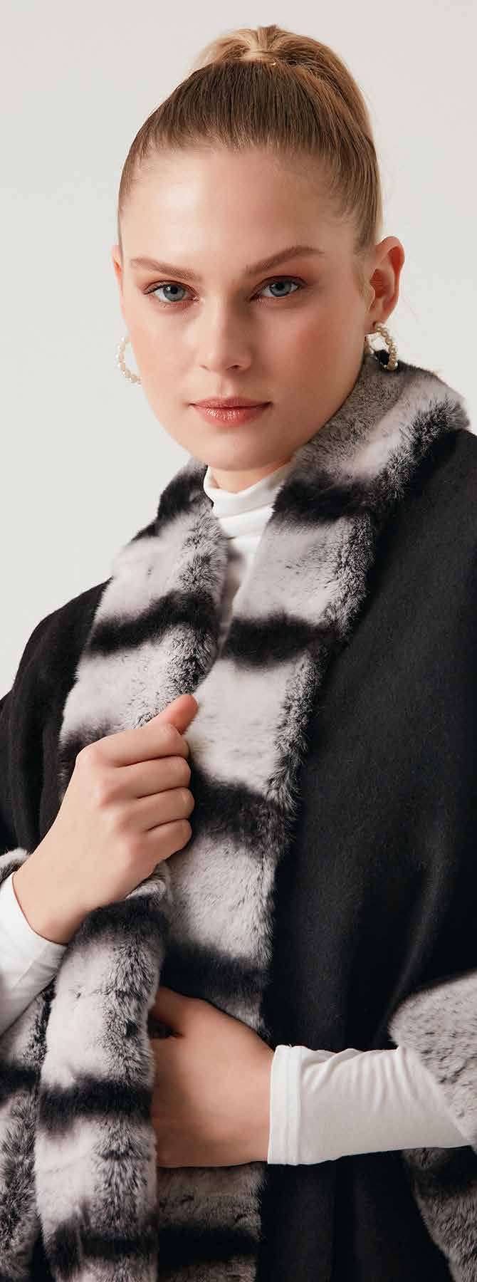 Woman wearing a black and gray rex fur alpaca poncho against a white background