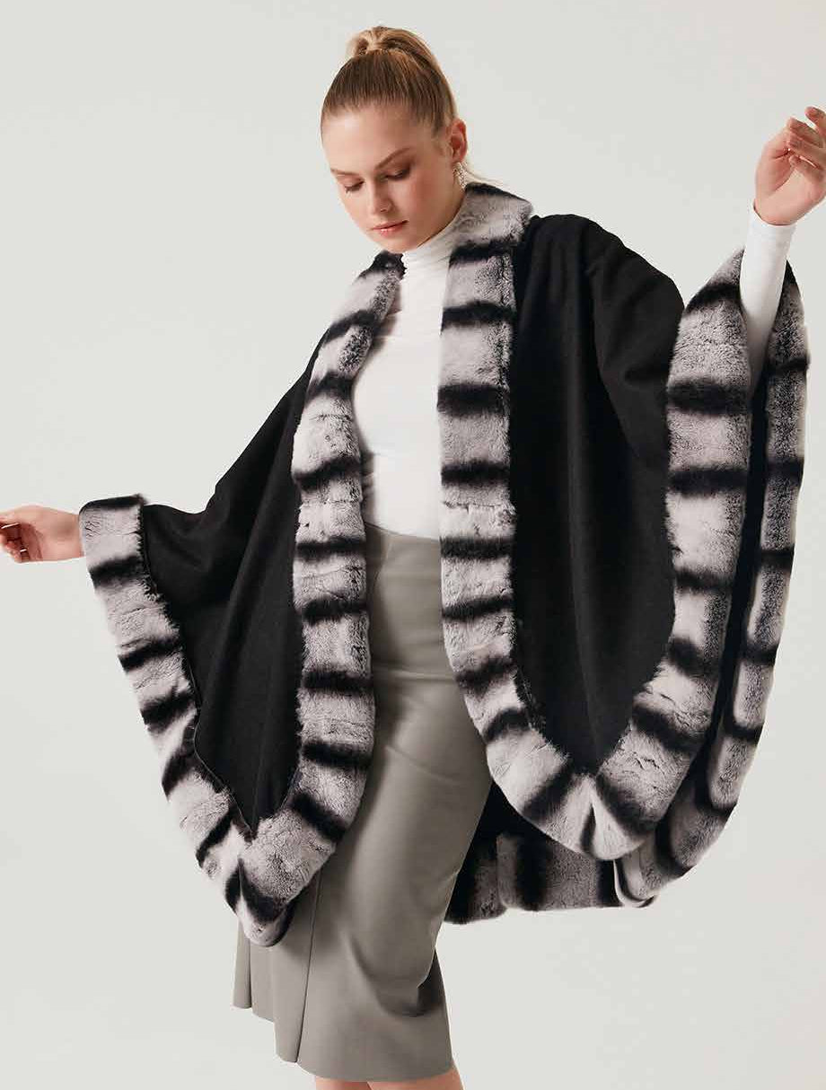 Woman wearing a black and gray rex fur striped alpaca poncho on a white background