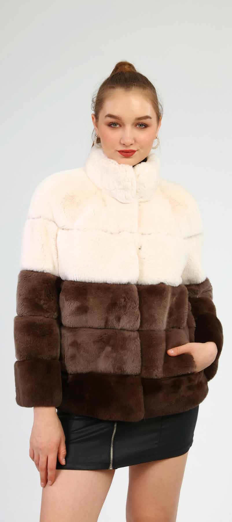 Woman wearing a two-tone fur jacket with white and brown sections on a plain background