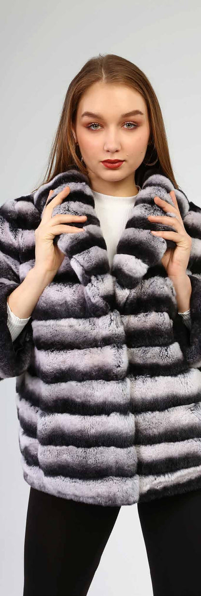 Woman wearing a gray and black striped fur coat on a light gray background