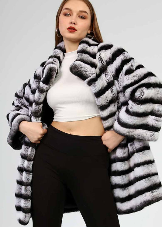 Woman wearing a black and white striped coat on a plain background