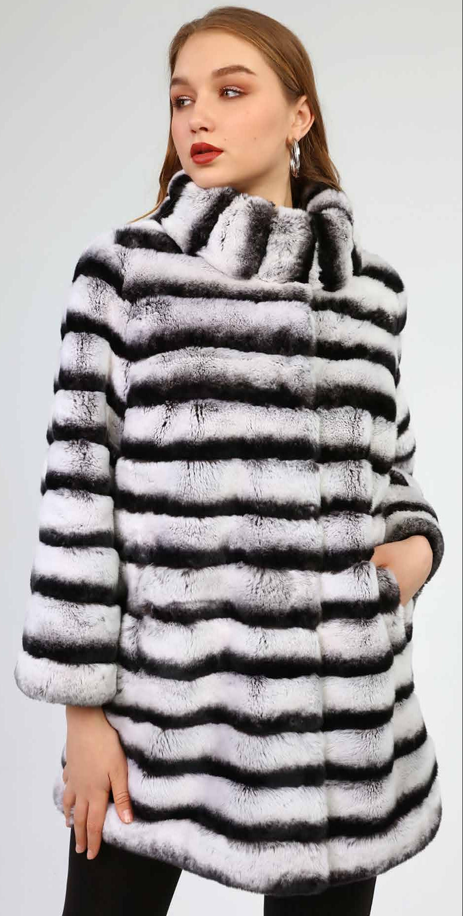 Woman wearing a black and white striped fur coat against a plain background