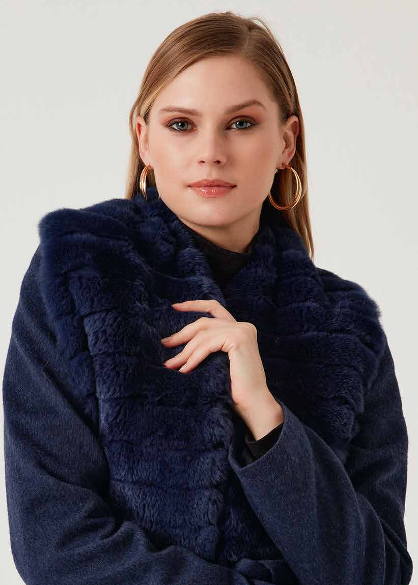 Woman wearing a navy blue coat with fur trim on a white background