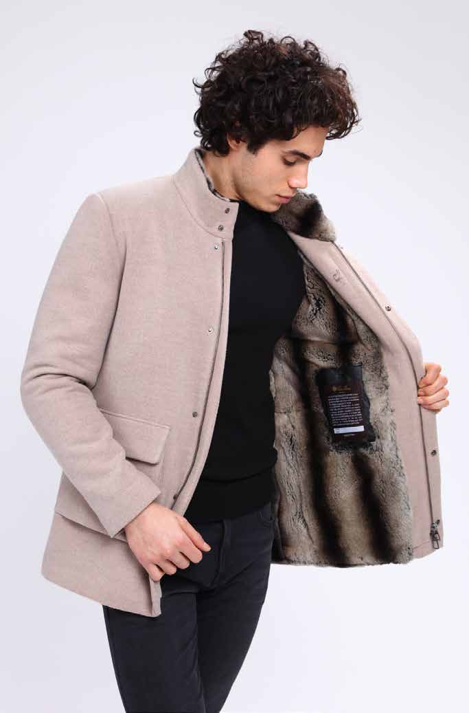 Man wearing a beige coat with fur lining, standing against a white background