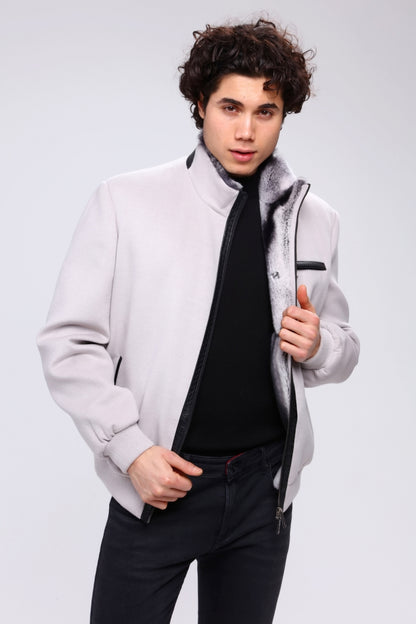 Man wearing a light gray jacket with a dark shirt and pants on a white background