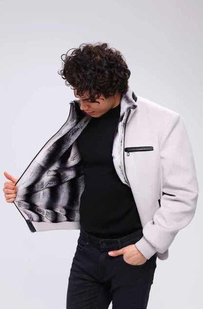 Man wearing a white jacket with a black and white patterned lining, standing against a plain background.