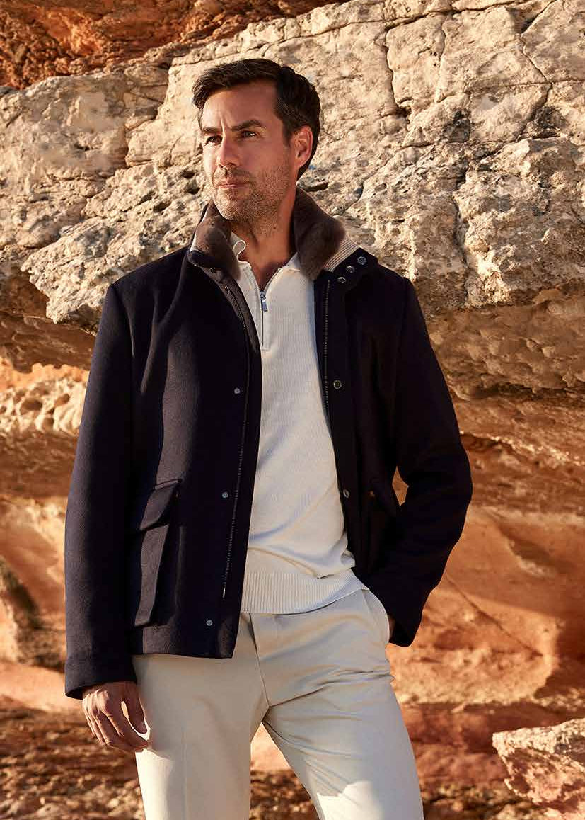 Man in dark jacket and light pants standing on rocky terrain