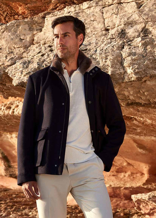 Man in dark jacket and light pants standing on rocky terrain