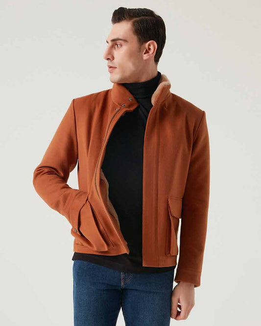 Man wearing a brown jacket, black shirt, blue jeans, and black boots on a white background