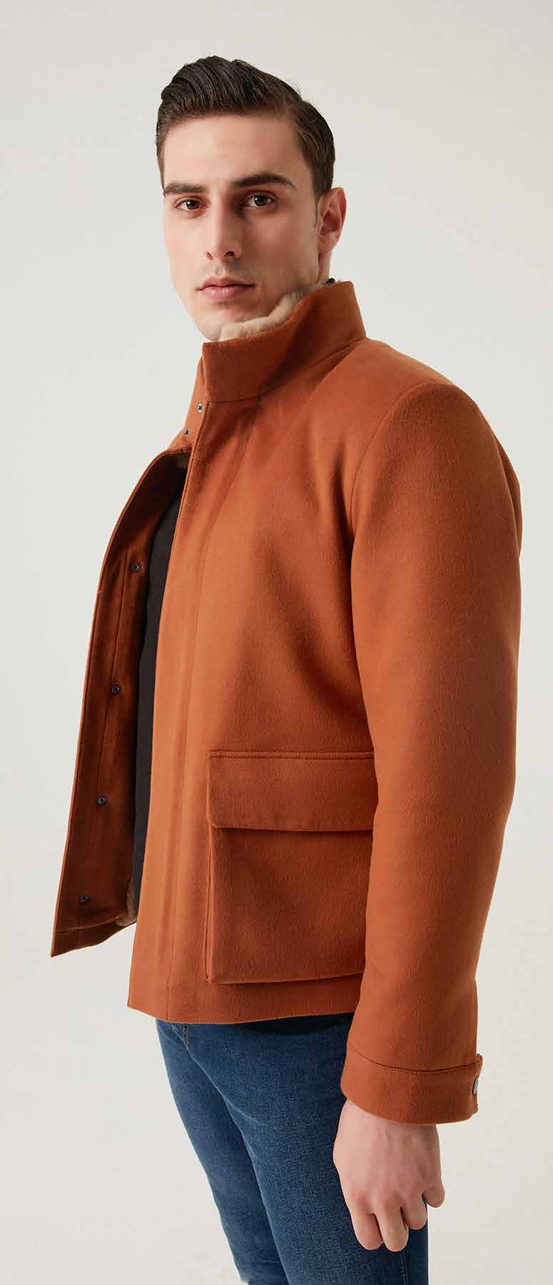 Man wearing a brown jacket and blue jeans on a white background