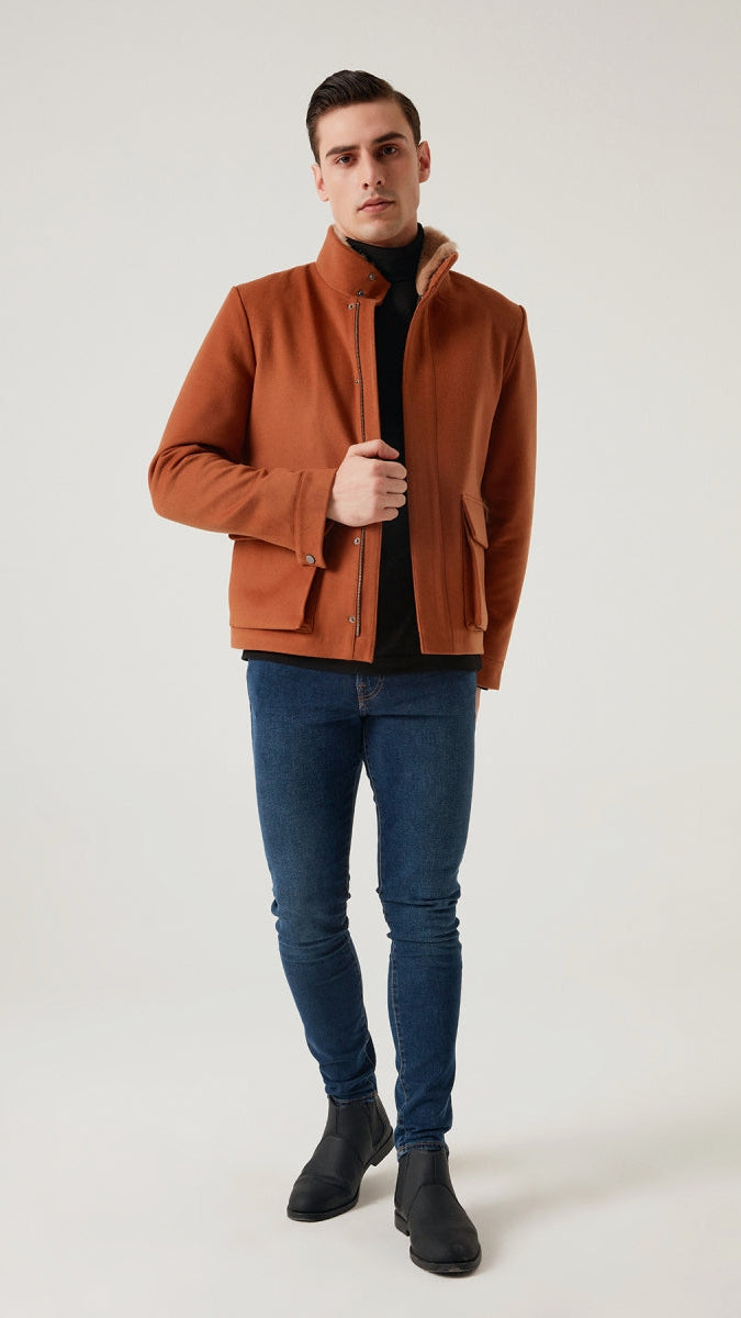 Man wearing a brown jacket, black shirt, blue jeans, and black shoes on a white background