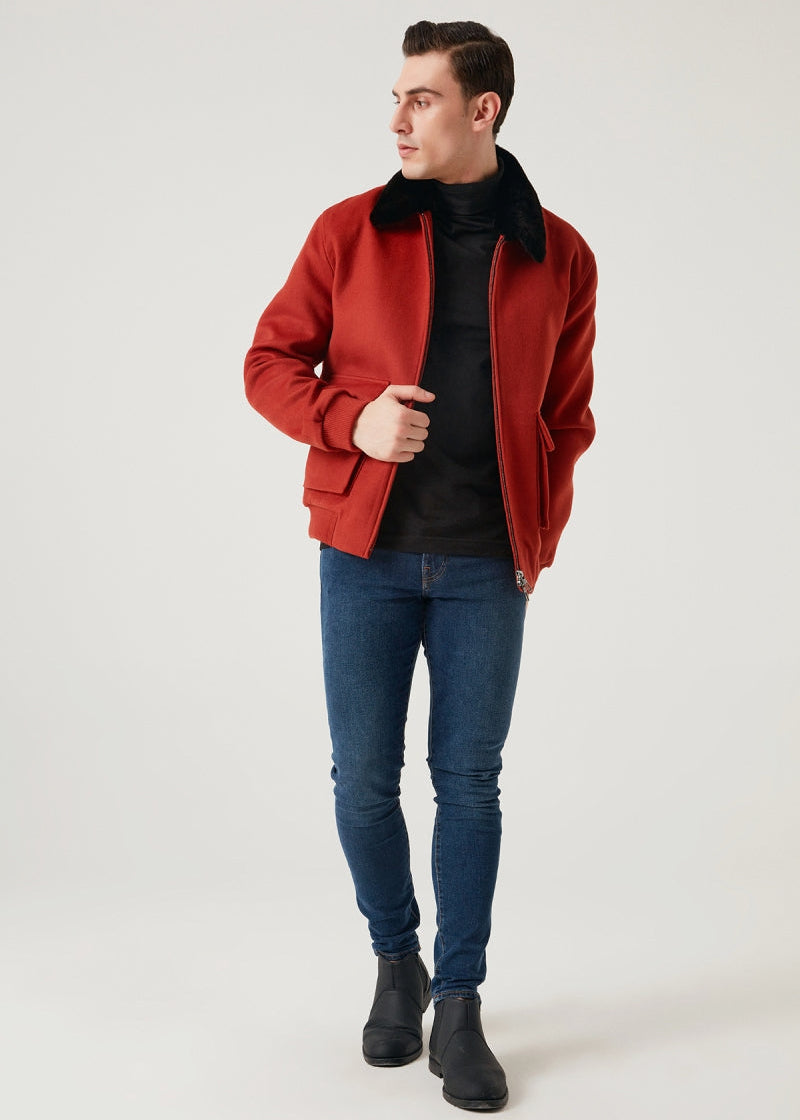 Man wearing a red jacket, black turtleneck, blue jeans, and black shoes on a white background