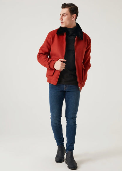 Man wearing a red jacket, black turtleneck, blue jeans, and black shoes on a white background