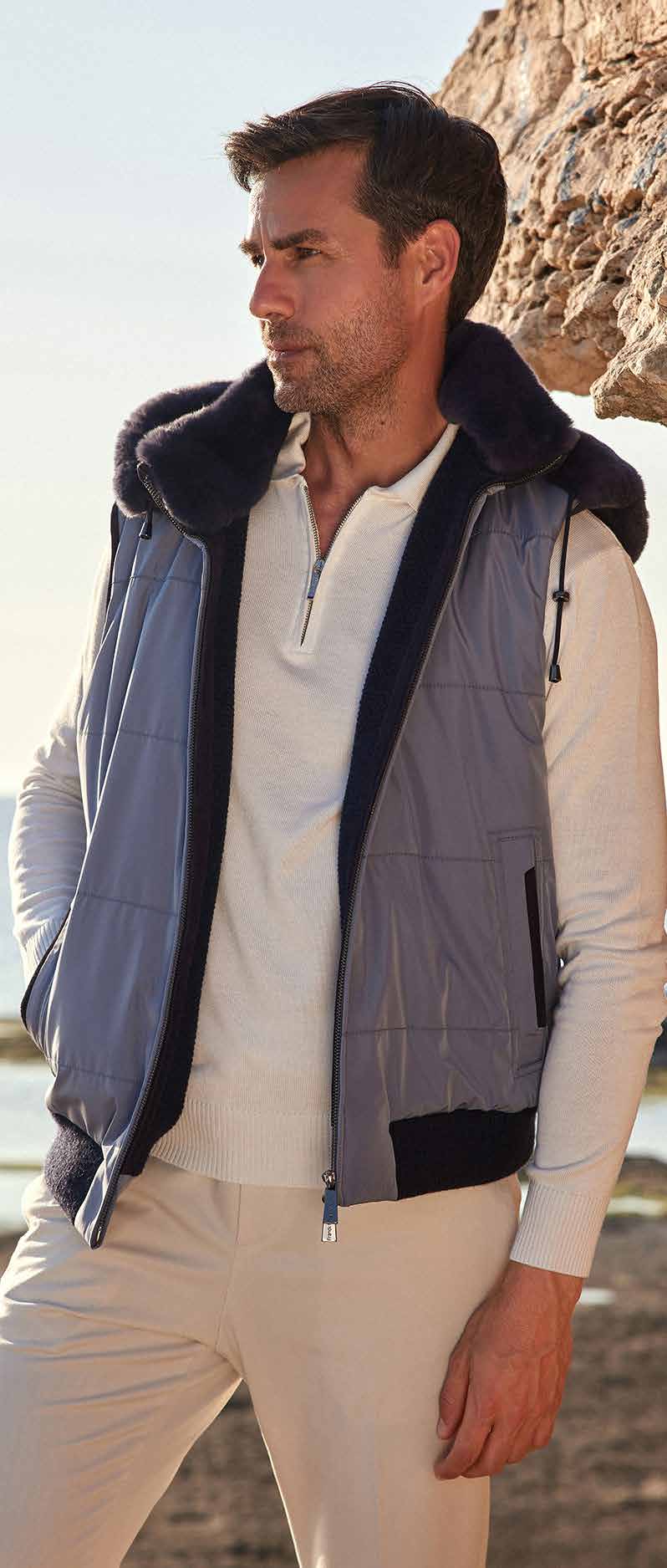 Man wearing a blue vest with black fur trim on a beach