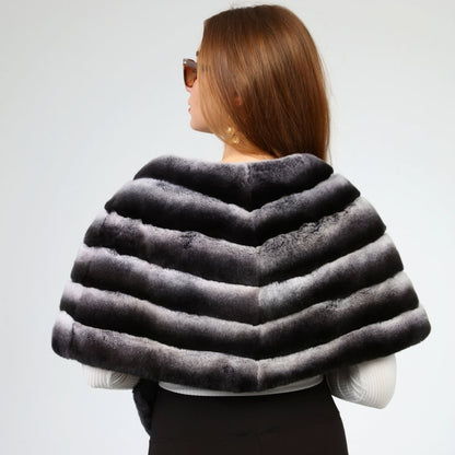 Woman wearing a dark gray rex fur shawl over a black outfit on a light gray background