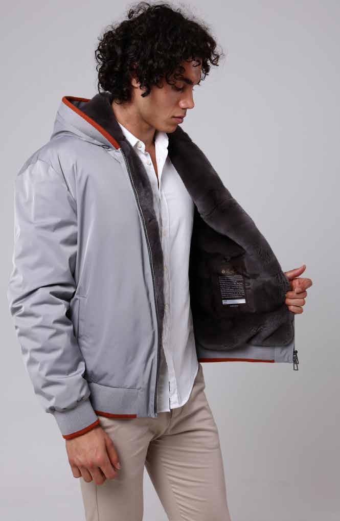 Man wearing a gray jacket with a fur-lined hood against a plain background