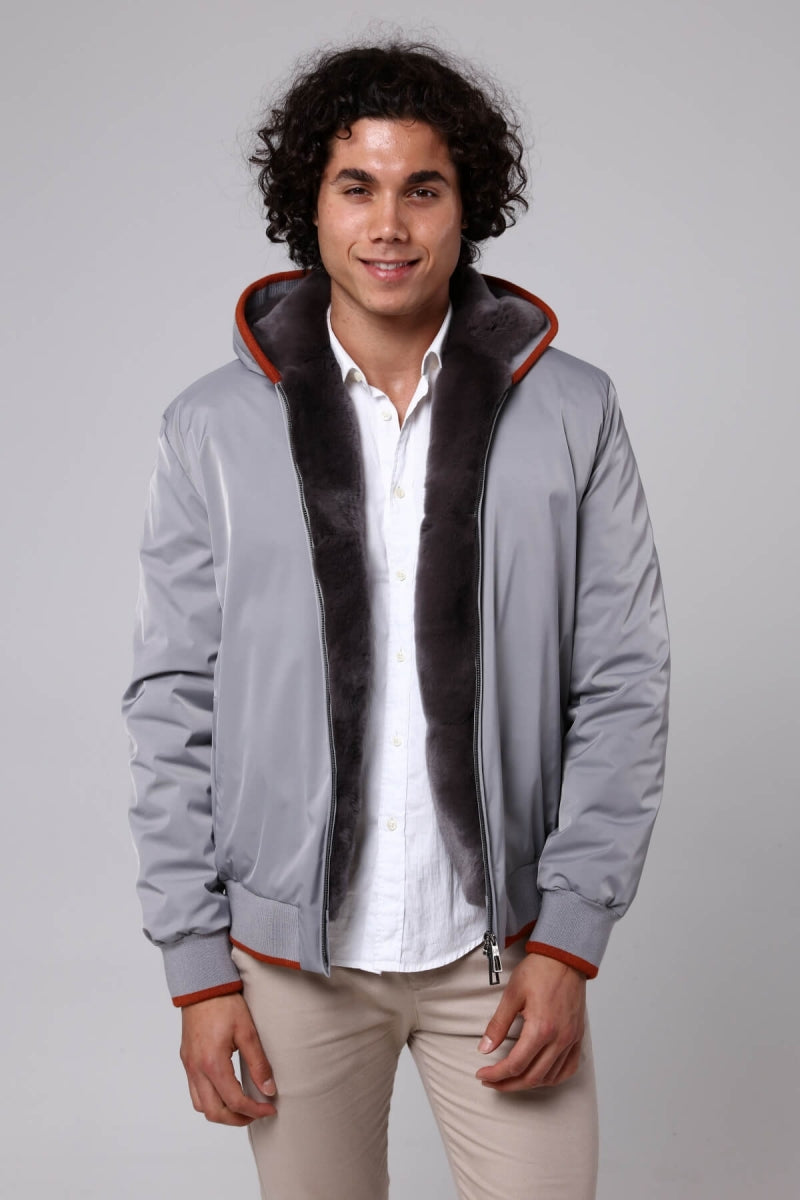 Man wearing a gray jacket with a fur-lined hood on a plain background