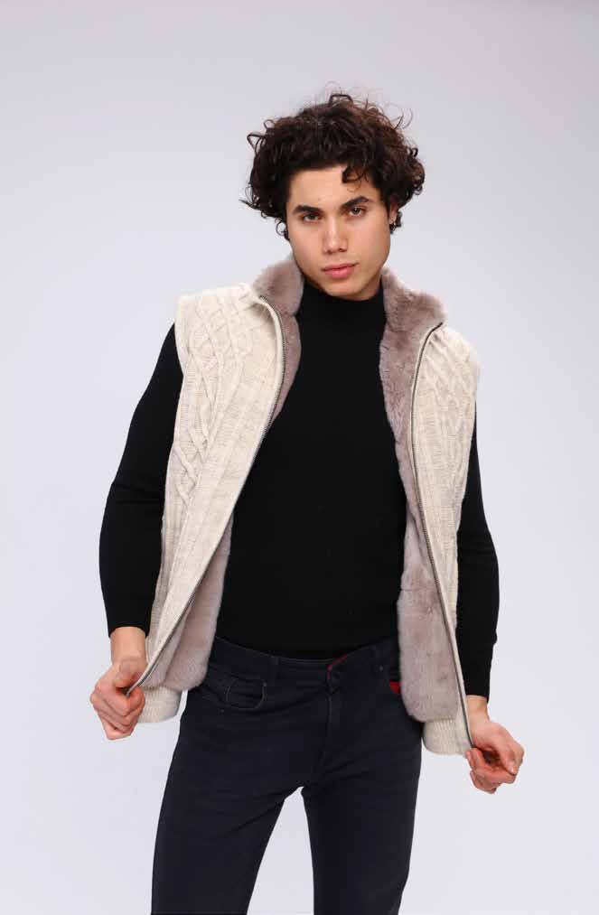 Man wearing a black turtleneck, dark jeans, and a beige quilted vest on a white background