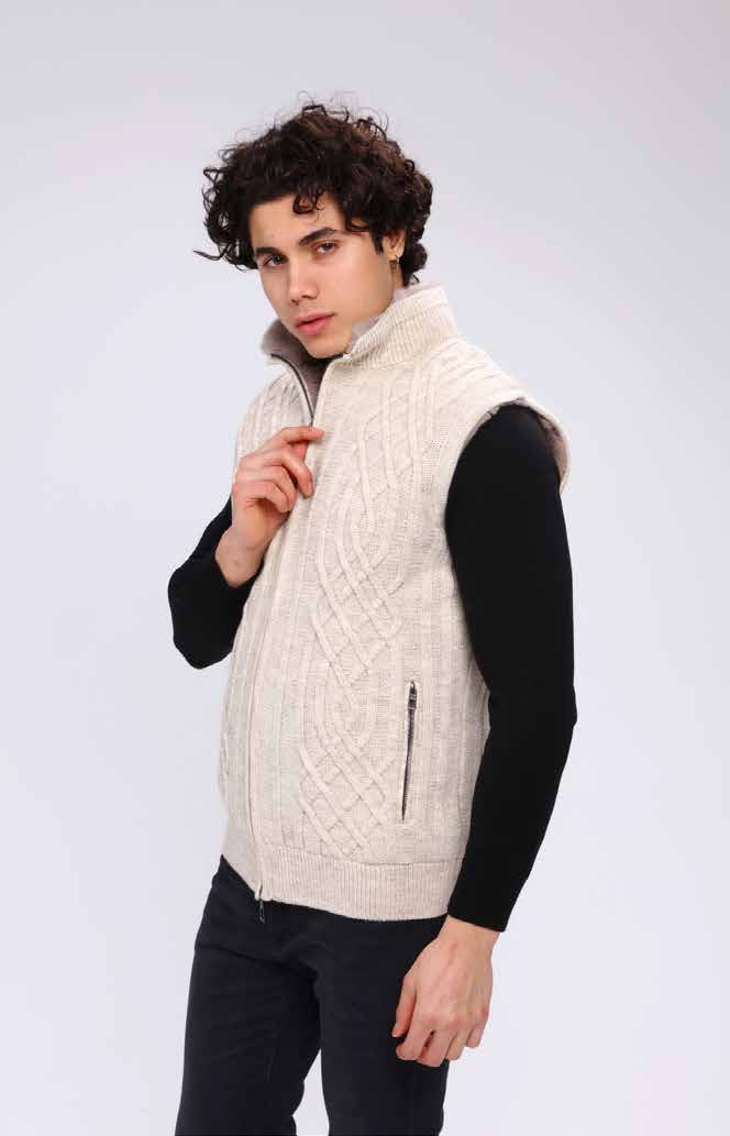 Man wearing a cream-colored cable knit vest against a white background