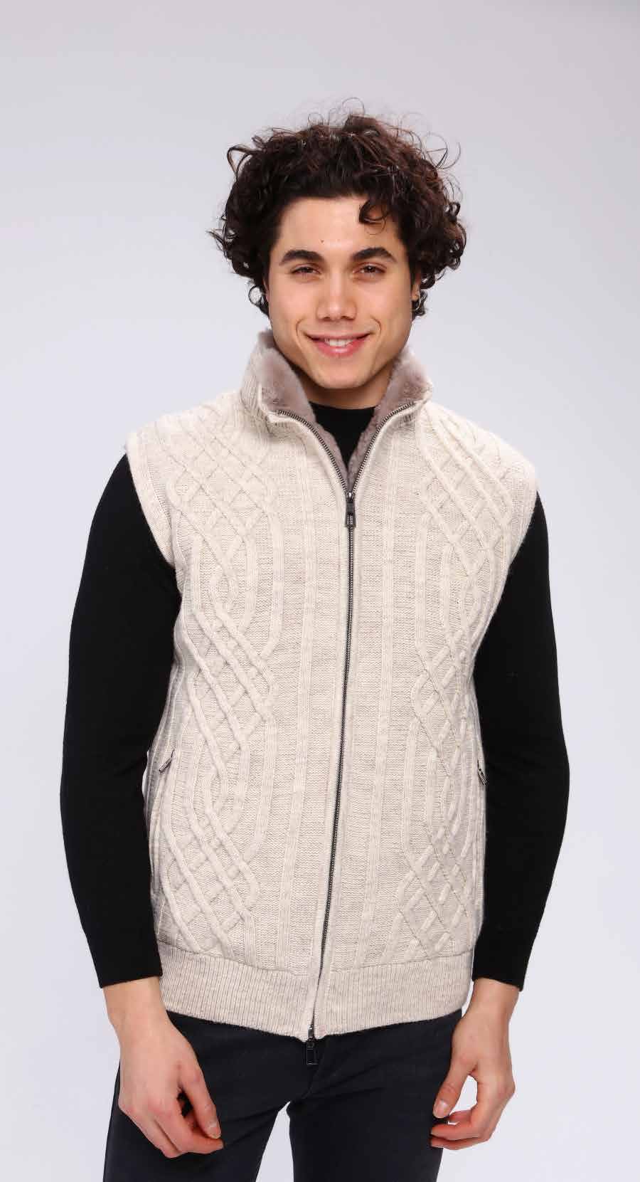 Man wearing a cream-colored vest over a black long-sleeve shirt on a white background