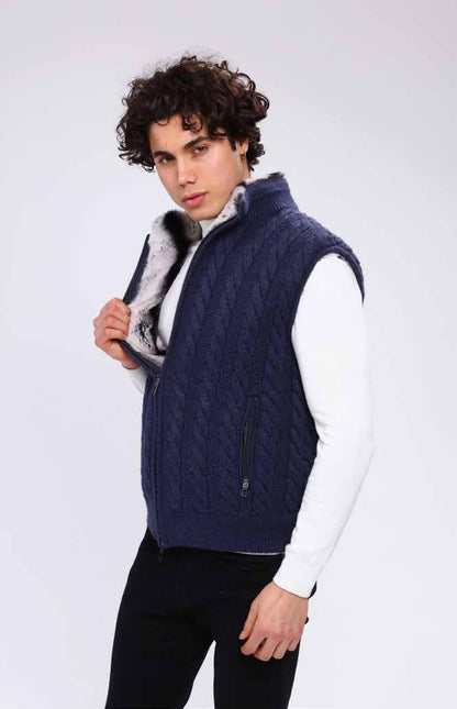 Man wearing a navy quilted vest with a white shirt and black pants on a light gray background