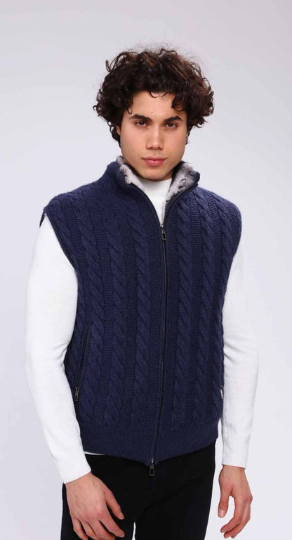 Person wearing a navy blue cable knit vest over a white shirt on a plain background
