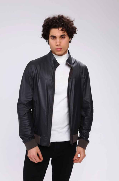 Man wearing a black leather jacket over a white shirt on a white background