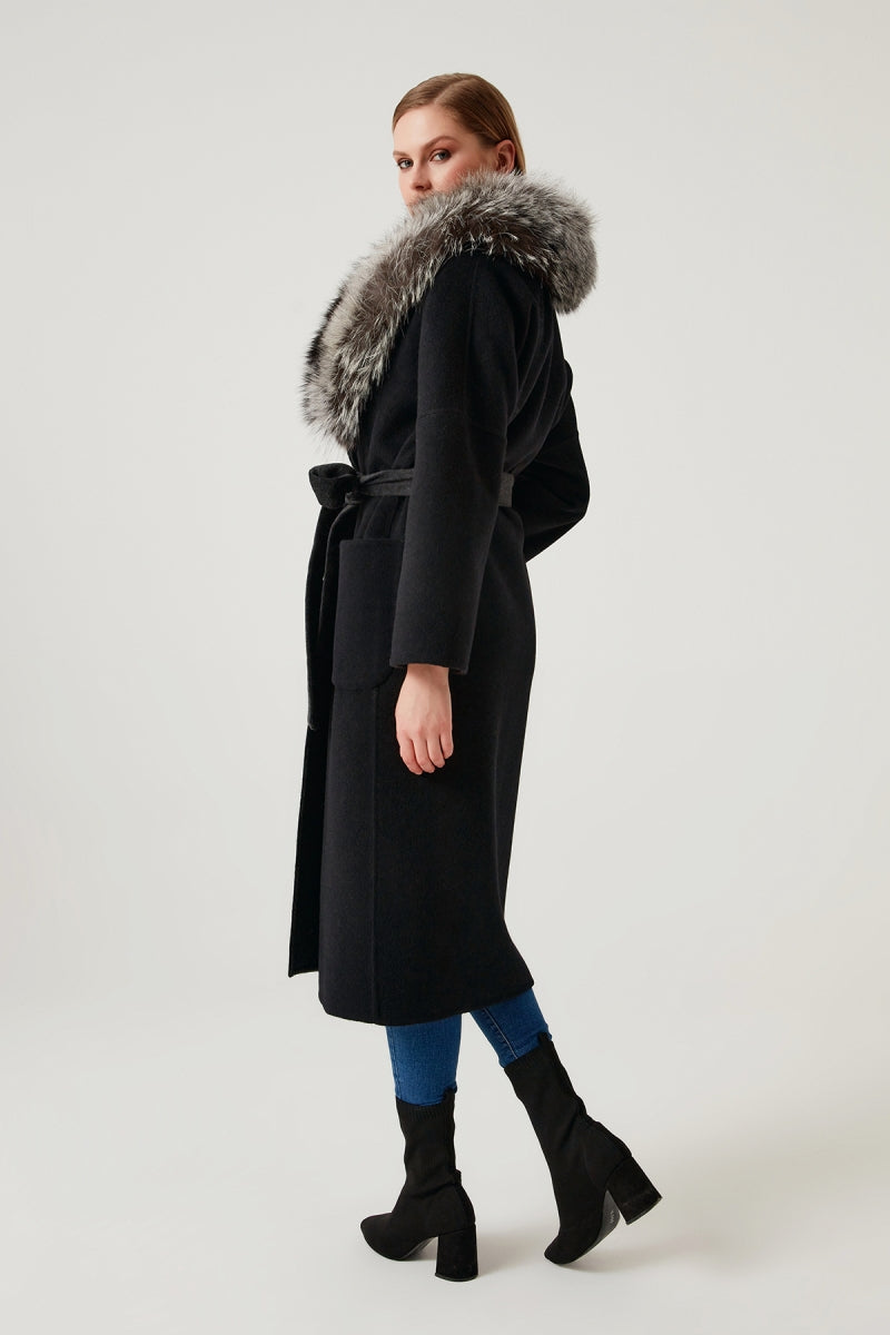 Woman wearing a black coat with a fur hood on a white background